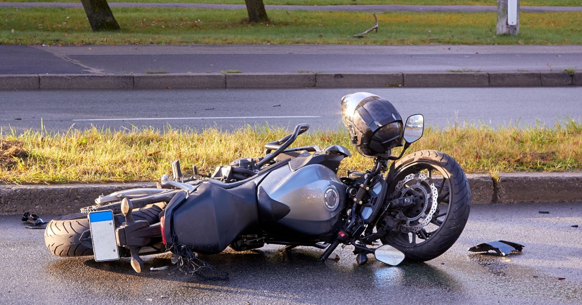 A black motorcycle on its side in the road after an accident with small pieces of debris nearby.